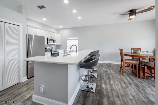 kitchen featuring white cabinets, a kitchen breakfast bar, a center island with sink, sink, and appliances with stainless steel finishes