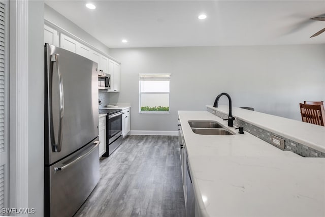 kitchen featuring sink, light stone countertops, appliances with stainless steel finishes, dark hardwood / wood-style flooring, and white cabinetry