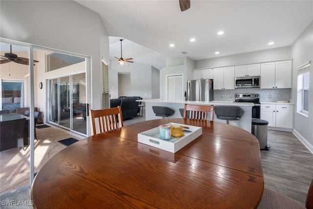 dining space featuring ceiling fan, light hardwood / wood-style flooring, and vaulted ceiling