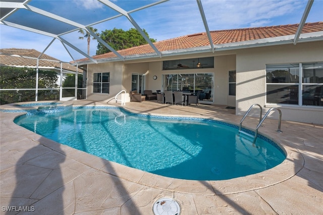 view of swimming pool with an in ground hot tub, a patio, glass enclosure, and ceiling fan