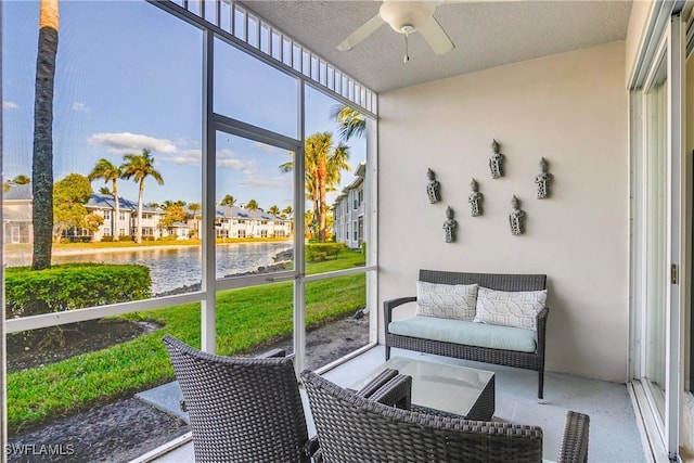 sunroom / solarium with ceiling fan and a water view