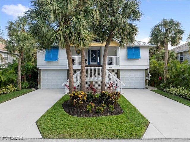 coastal inspired home with a front lawn, a porch, and a garage