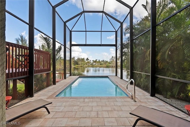 view of pool featuring glass enclosure, a water view, and a patio