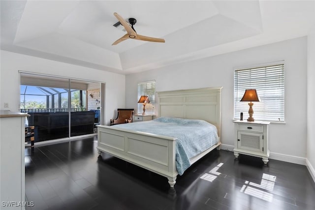 bedroom with dark hardwood / wood-style floors, a raised ceiling, and ceiling fan