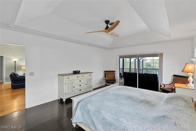 bedroom with access to outside, ceiling fan, hardwood / wood-style floors, and a tray ceiling