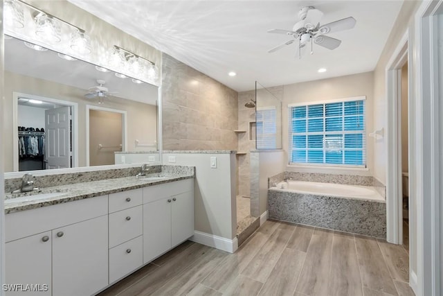 bathroom featuring hardwood / wood-style floors, ceiling fan, vanity, and plus walk in shower