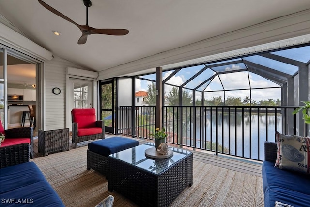 sunroom / solarium with ceiling fan, a water view, a wealth of natural light, and vaulted ceiling