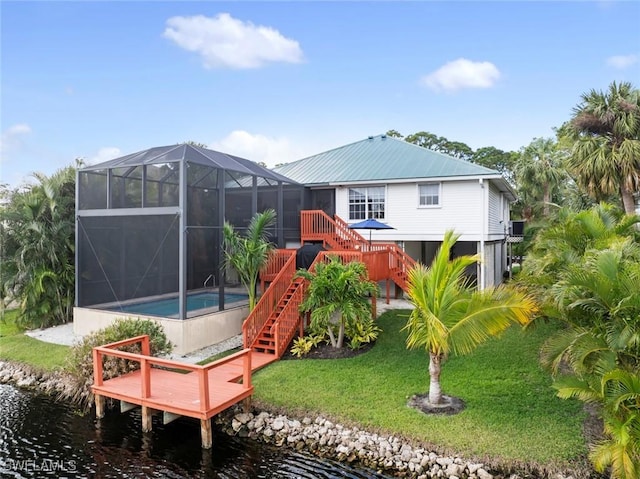 back of house with a lanai, a yard, and a water view