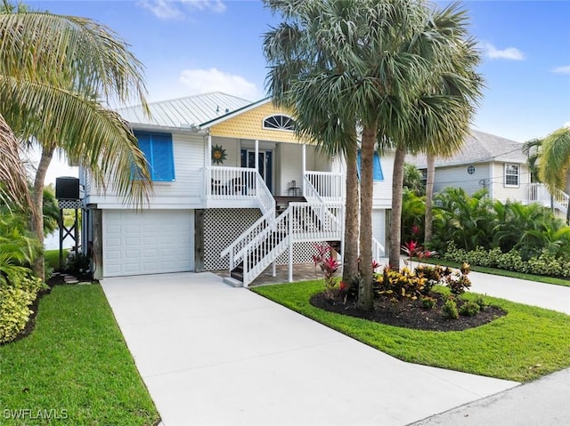 coastal inspired home featuring a garage, covered porch, and a front yard