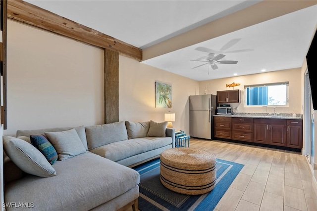 living room featuring beam ceiling, ceiling fan, light hardwood / wood-style flooring, and sink