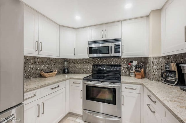 kitchen with light stone counters, white cabinetry, and stainless steel appliances