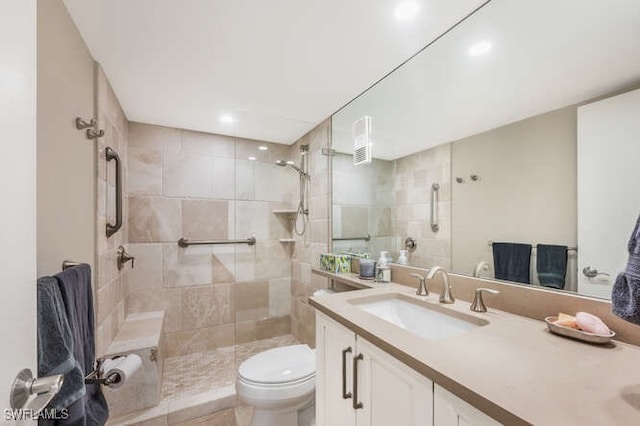 bathroom with tile patterned flooring, vanity, toilet, and tiled shower