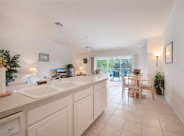 kitchen featuring ceiling fan, sink, white cabinets, lofted ceiling, and light tile patterned flooring