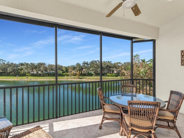 sunroom with ceiling fan and a water view