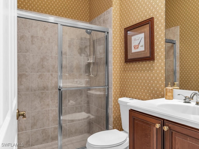 bathroom featuring vanity, toilet, and a shower with shower door