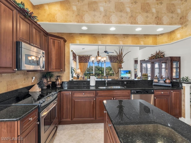 kitchen featuring ceiling fan with notable chandelier, sink, dark stone countertops, light tile patterned floors, and stainless steel appliances