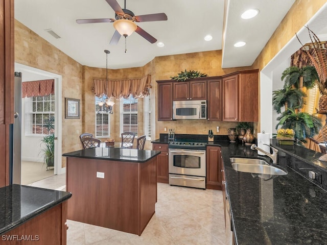 kitchen with dark stone countertops, sink, a center island, and appliances with stainless steel finishes