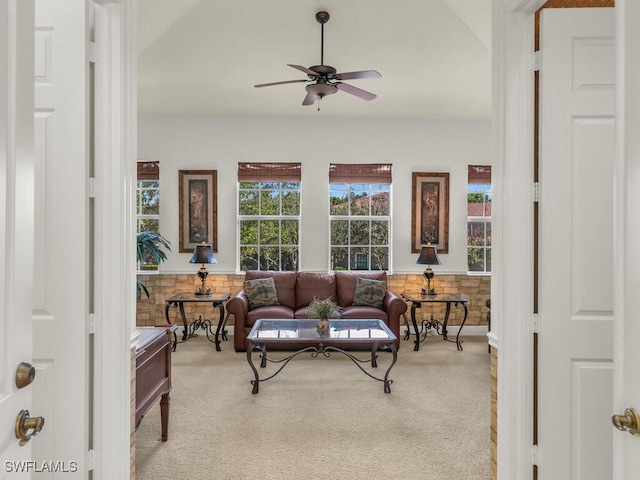 carpeted living room with ceiling fan and wood walls