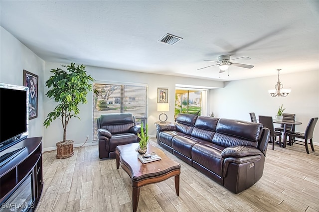 living room with ceiling fan with notable chandelier and light hardwood / wood-style floors