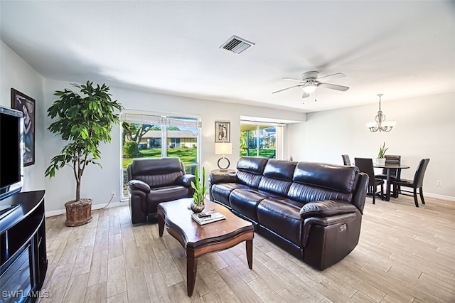 living room featuring ceiling fan with notable chandelier and light wood-type flooring