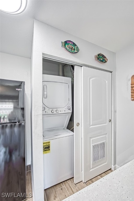 clothes washing area featuring stacked washer / dryer and light wood-type flooring