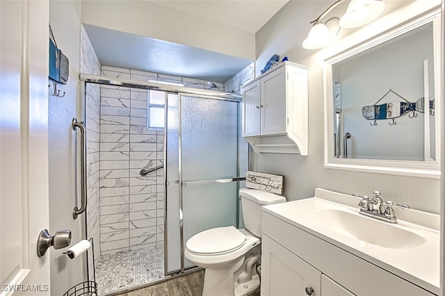 bathroom with hardwood / wood-style floors, vanity, a shower with door, and toilet