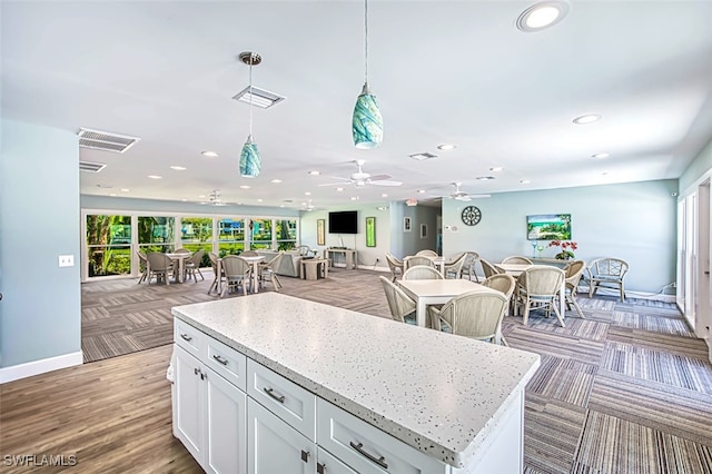 kitchen featuring pendant lighting, ceiling fan, light hardwood / wood-style floors, a kitchen island, and white cabinetry