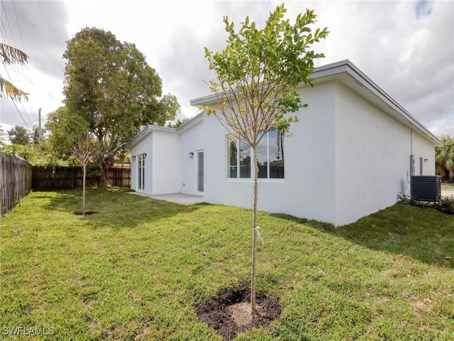 rear view of property with a lawn, central AC, and a patio