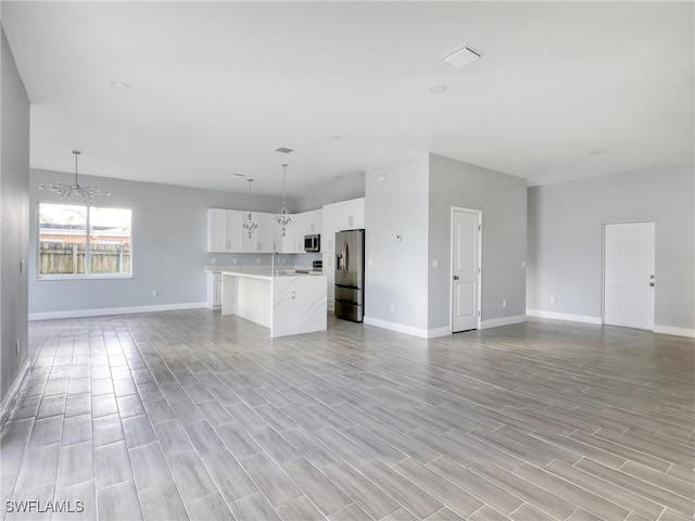 unfurnished living room with light wood-type flooring and a notable chandelier