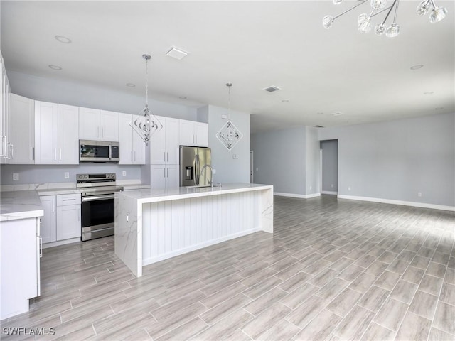 kitchen with light wood-type flooring, stainless steel appliances, a kitchen island, and white cabinetry