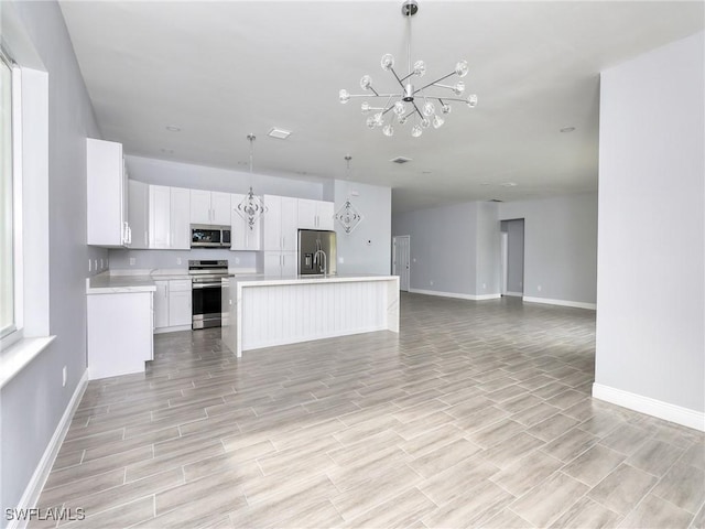 kitchen with a center island, white cabinets, light hardwood / wood-style flooring, appliances with stainless steel finishes, and decorative light fixtures