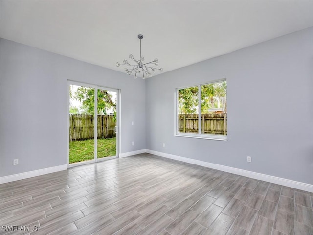 spare room featuring a notable chandelier and light wood-type flooring