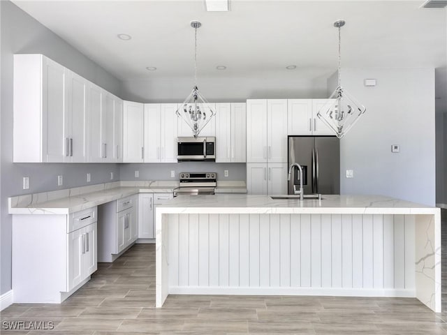 kitchen featuring a center island with sink, decorative light fixtures, sink, and stainless steel appliances