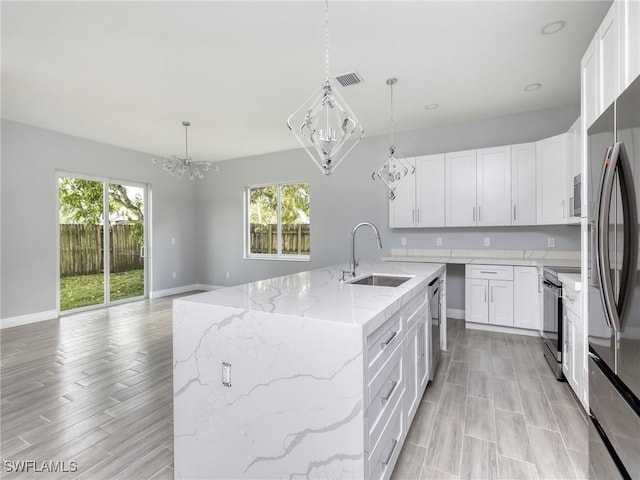 kitchen featuring appliances with stainless steel finishes, sink, pendant lighting, a center island with sink, and white cabinetry