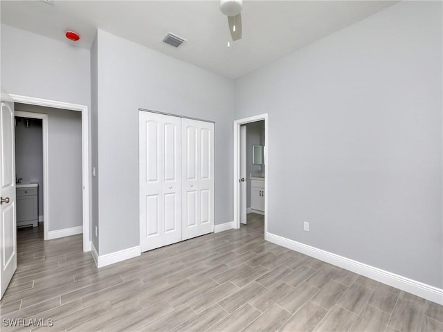 unfurnished bedroom with ceiling fan, a closet, ensuite bathroom, and light wood-type flooring