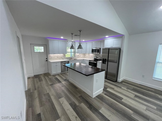 kitchen featuring dark hardwood / wood-style flooring, stainless steel appliances, pendant lighting, a kitchen island, and lofted ceiling