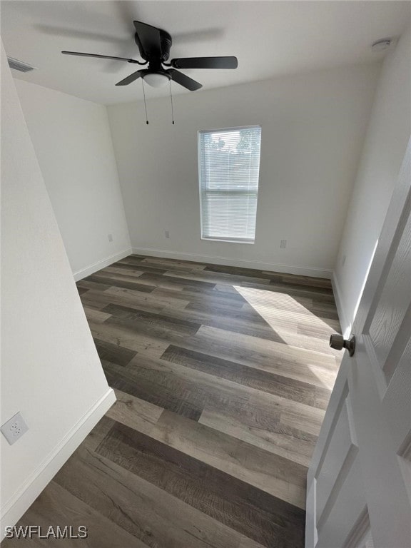 empty room with ceiling fan and dark hardwood / wood-style flooring