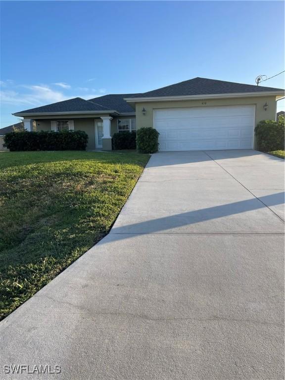 ranch-style house featuring a garage and a front lawn