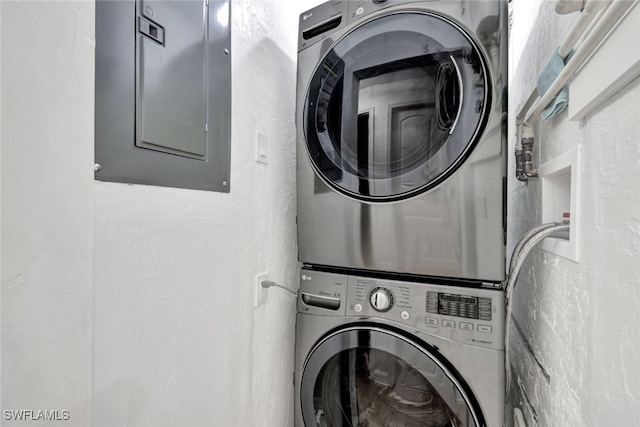 laundry area with electric panel and stacked washer / drying machine