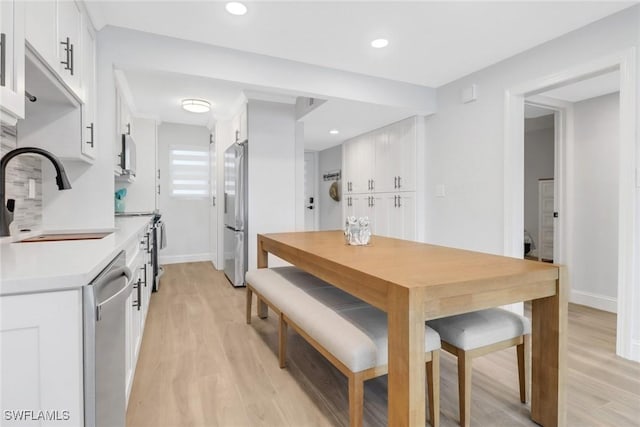 interior space featuring white cabinets, sink, appliances with stainless steel finishes, and light hardwood / wood-style flooring