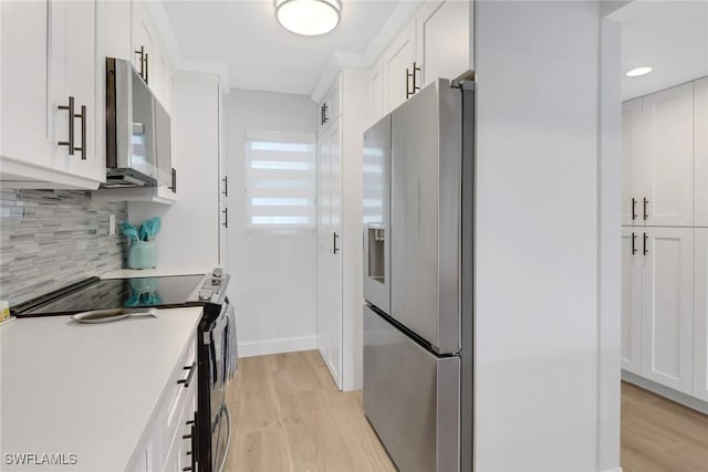 kitchen with white cabinets, tasteful backsplash, stainless steel appliances, and light hardwood / wood-style flooring