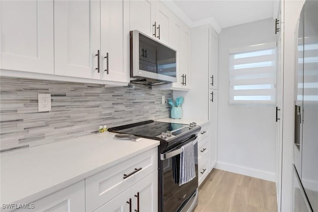 kitchen with backsplash, black / electric stove, white cabinetry, and light hardwood / wood-style flooring