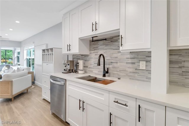 kitchen with tasteful backsplash, sink, white cabinets, and stainless steel dishwasher