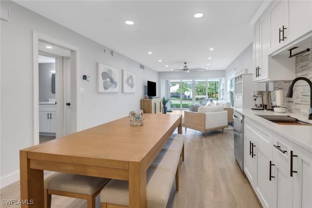 dining room with ceiling fan, light wood-type flooring, and sink