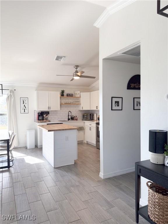 kitchen featuring white cabinets, light wood-type flooring, ornamental molding, and sink