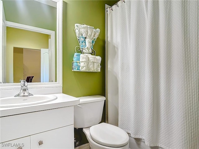 bathroom featuring toilet, vanity, and curtained shower