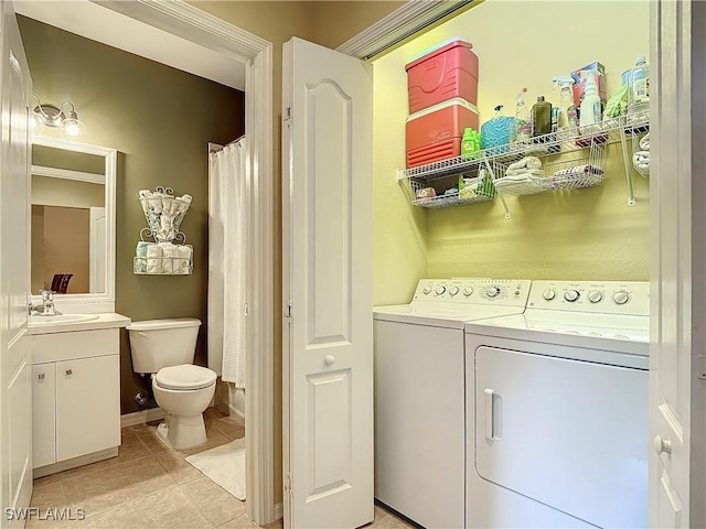 washroom with light tile patterned flooring, sink, and washing machine and clothes dryer