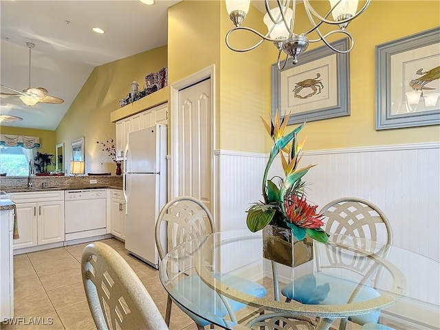 tiled dining room with vaulted ceiling, ceiling fan with notable chandelier, and sink