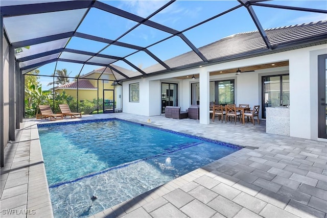 outdoor pool featuring glass enclosure, outdoor dining area, a patio area, and a ceiling fan