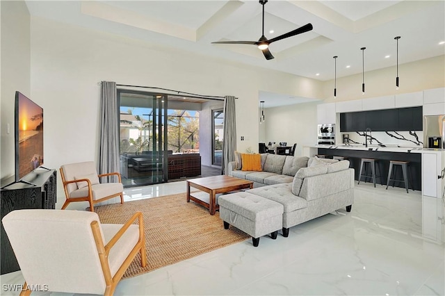 living room featuring beam ceiling, ceiling fan, a towering ceiling, and coffered ceiling